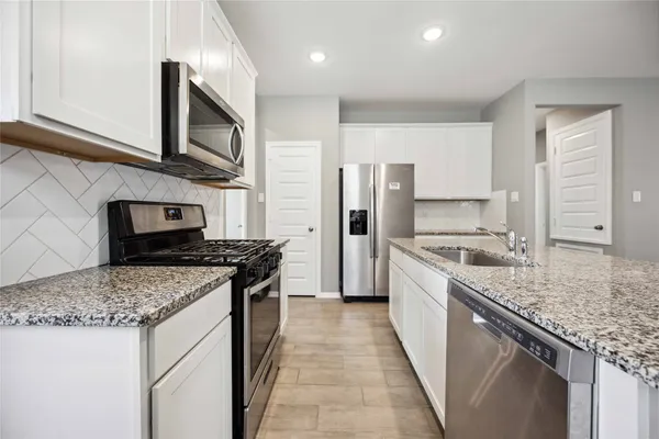 a kitchen with stainless steel appliances granite countertop a sink stove and refrigerator