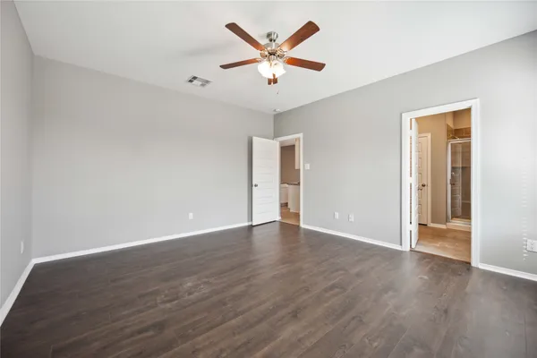 an empty room with wooden floor and ceiling fan