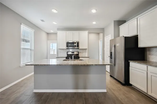 a kitchen with kitchen island a sink a center island stainless steel appliances and cabinets