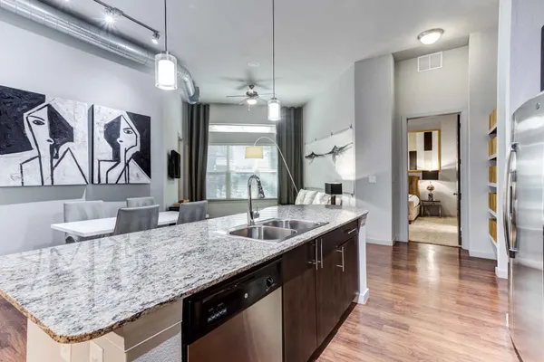 a kitchen with granite countertop kitchen island stainless steel appliances a sink stove and wooden floor