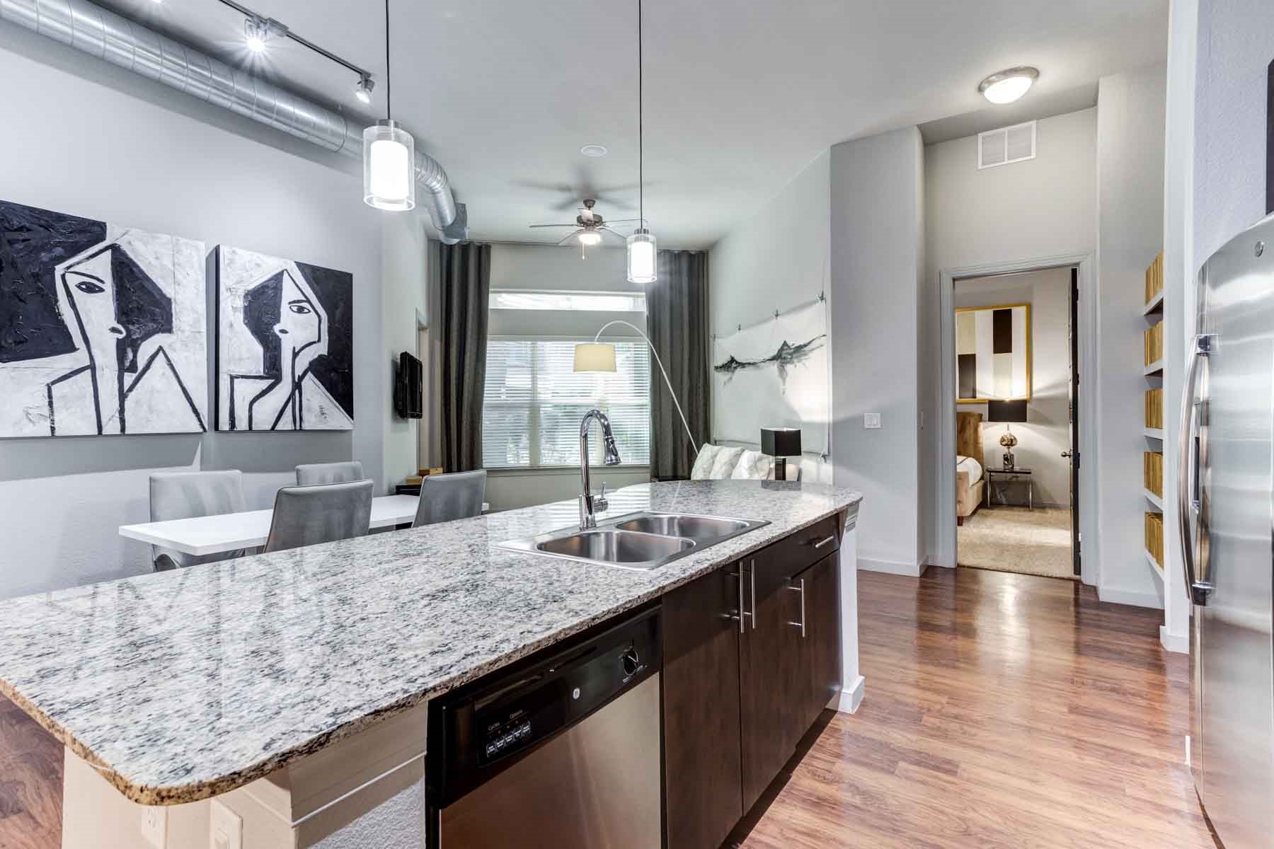 2525 McCue Road, Unit 519 Houston, TX 77056 - Photo 5 of 15 a kitchen with granite countertop kitchen island stainless steel appliances a sink stove and wooden floor