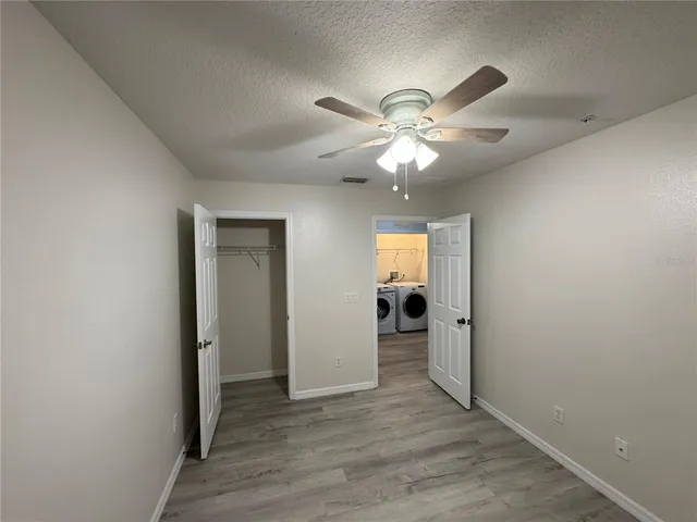 an empty room with wooden floor fan and windows