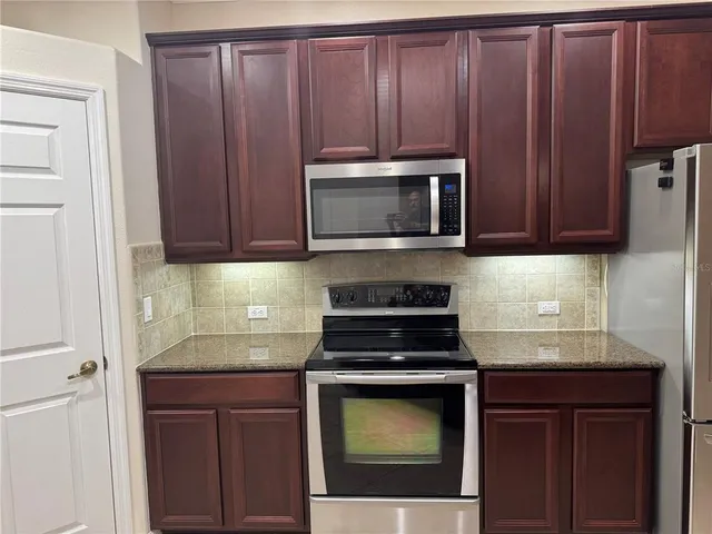 a kitchen with granite countertop wooden cabinets and stainless steel appliances