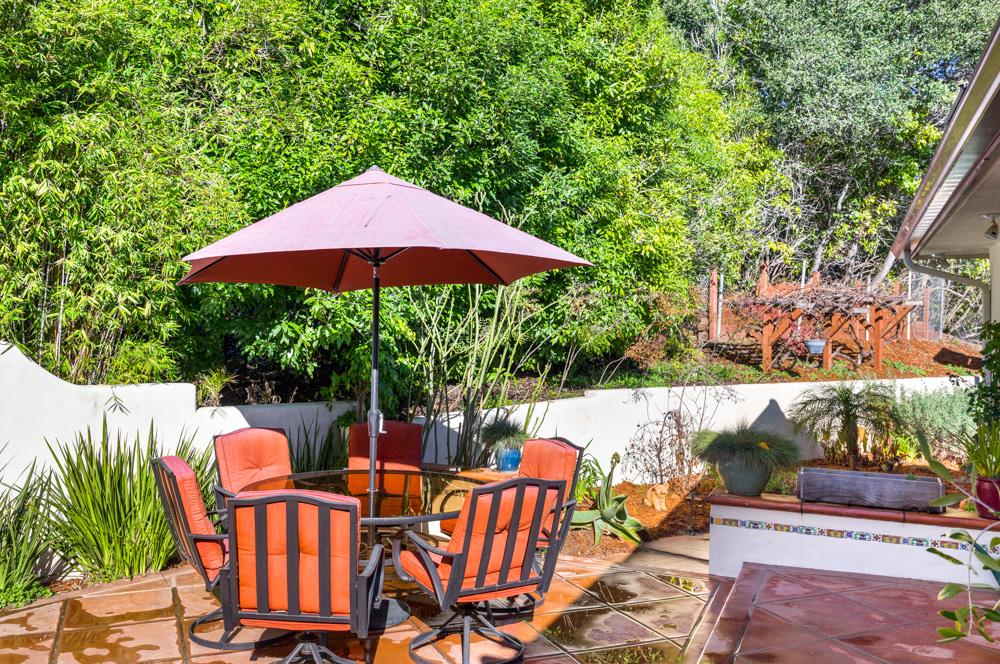 115 Santa Fe Ridge Aptos, CA 95003 - Photo 38 of 50 a backyard of a house with table and chairs under an umbrella