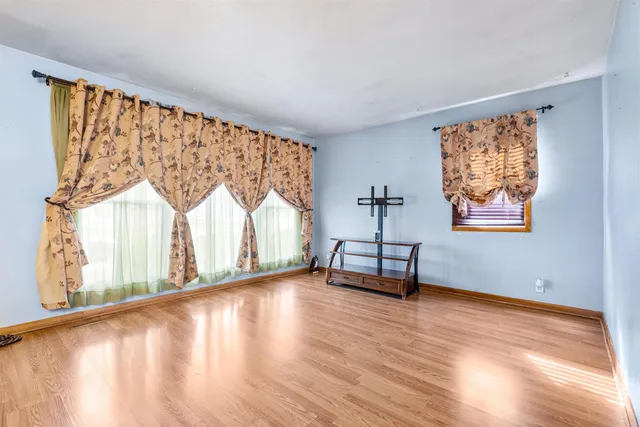 a view of an empty room with window a ceiling fan and wooden floor
