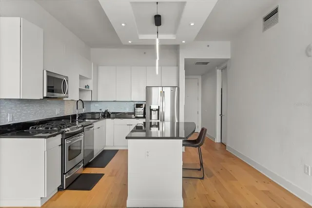 a kitchen with kitchen island stainless steel appliances a stove refrigerator sink and microwave