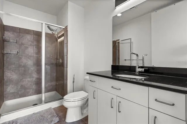 a bathroom with a granite countertop sink a toilet a mirror and shower