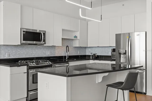 a kitchen with granite countertop a refrigerator stove and microwave