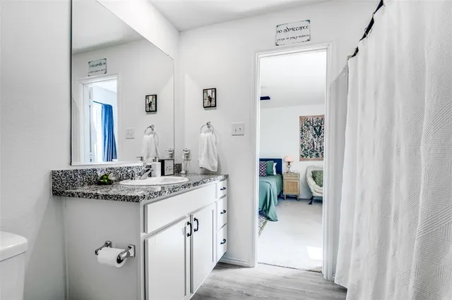 a en suite bathroom with a granite countertop sink and a mirror