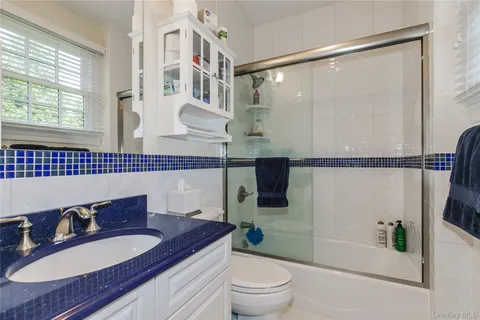 a bathroom with a granite countertop sink toilet a mirror a bathtub and shower