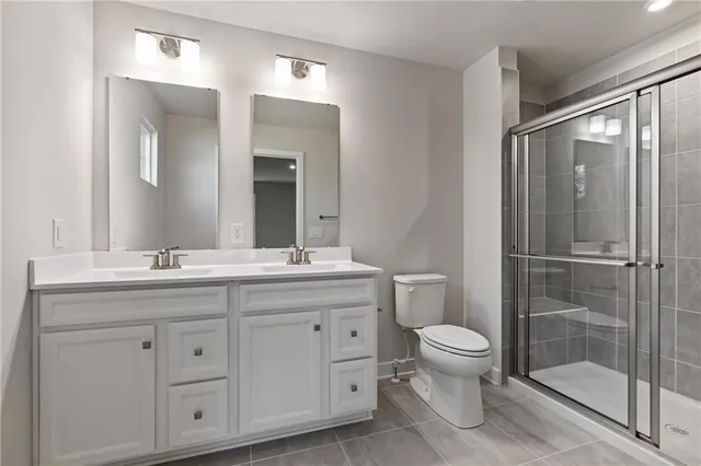 a bathroom with a granite countertop toilet a sink a mirror and a shower