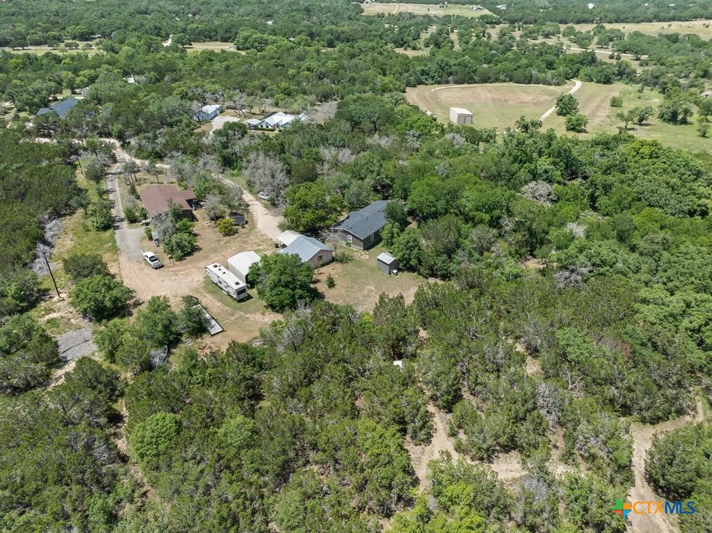 an aerial view of residential house with outdoor space and trees all around
