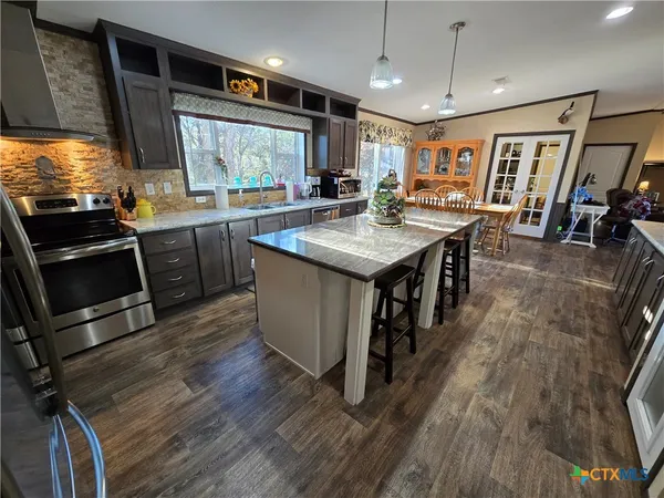 a kitchen with stainless steel appliances granite countertop a stove and a wooden floors