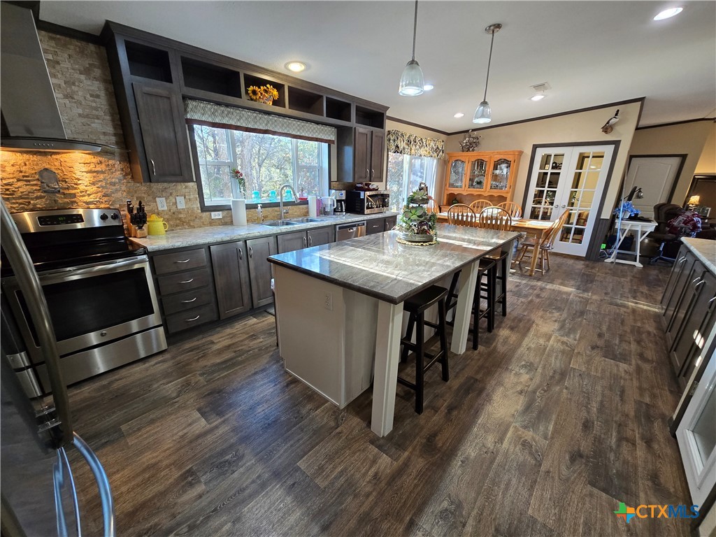 390-400 North Fawn Ridge Drive Leander, TX 78641 - Photo 13 of 48 a kitchen with stainless steel appliances granite countertop a stove and a wooden floors