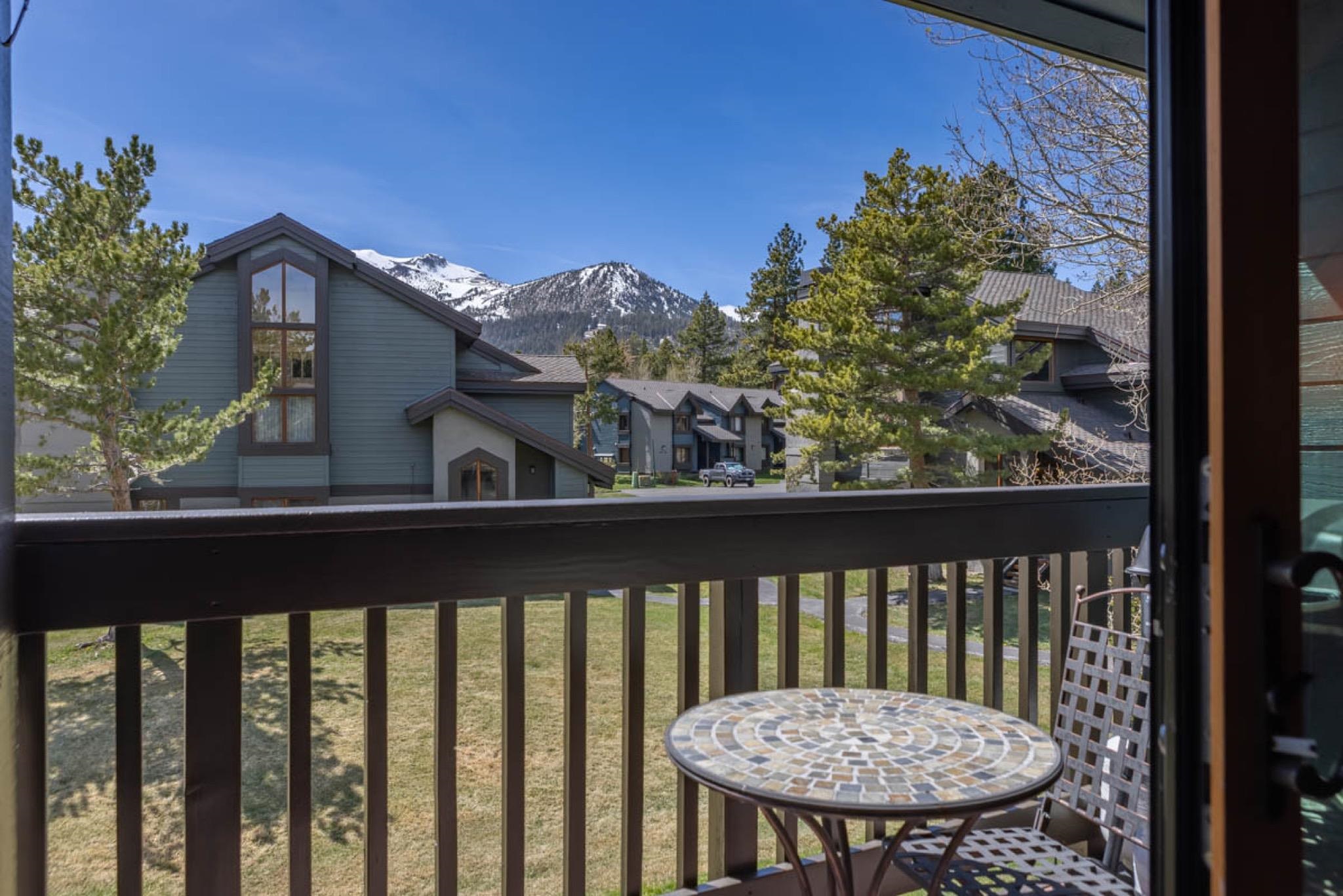 Balcony offering a mountain backdrop, a clear blue sky, and surrounding evergreen trees