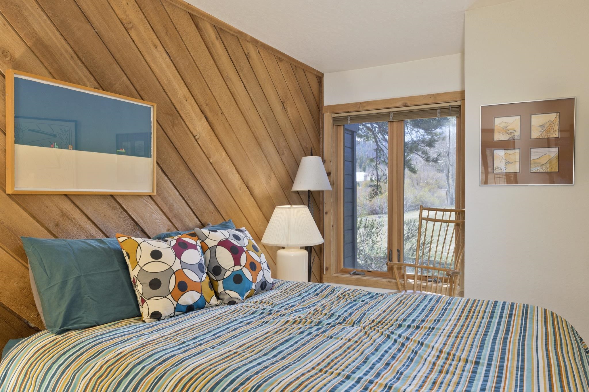 417 Snowcreek Road, Unit 417 Mammoth Lakes, CA 93546 - Photo 23 of 31 Wood-paneled accent wall in warm tones, large window with wood trim, and neutral painted walls
