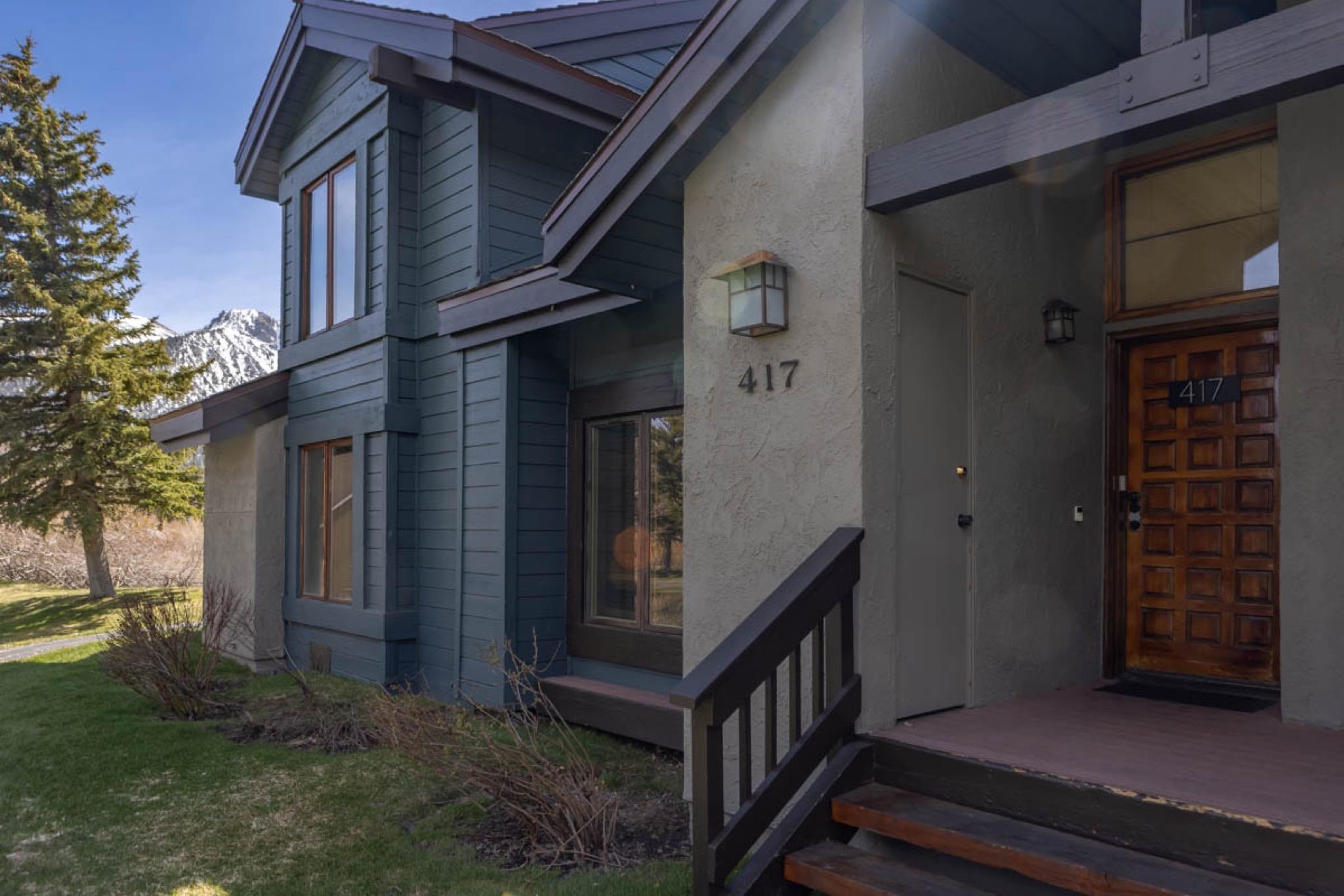 417 Snowcreek Road, Unit 417 Mammoth Lakes, CA 93546 - Photo 3 of 31 Contemporary multi-level residence featuring a carved wood entry door, stucco and plank siding exterior, and a prominent mountain backdrop
