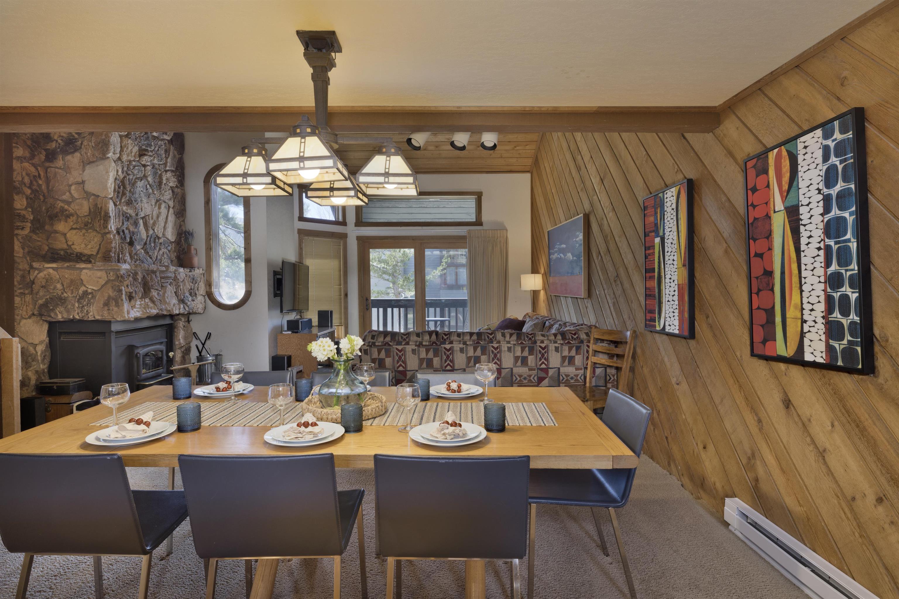 417 Snowcreek Road, Unit 417 Mammoth Lakes, CA 93546 - Photo 5 of 31 Spacious dining area featuring a prominent stone fireplace, wood-plank accent wall, and a multi-light chandelier