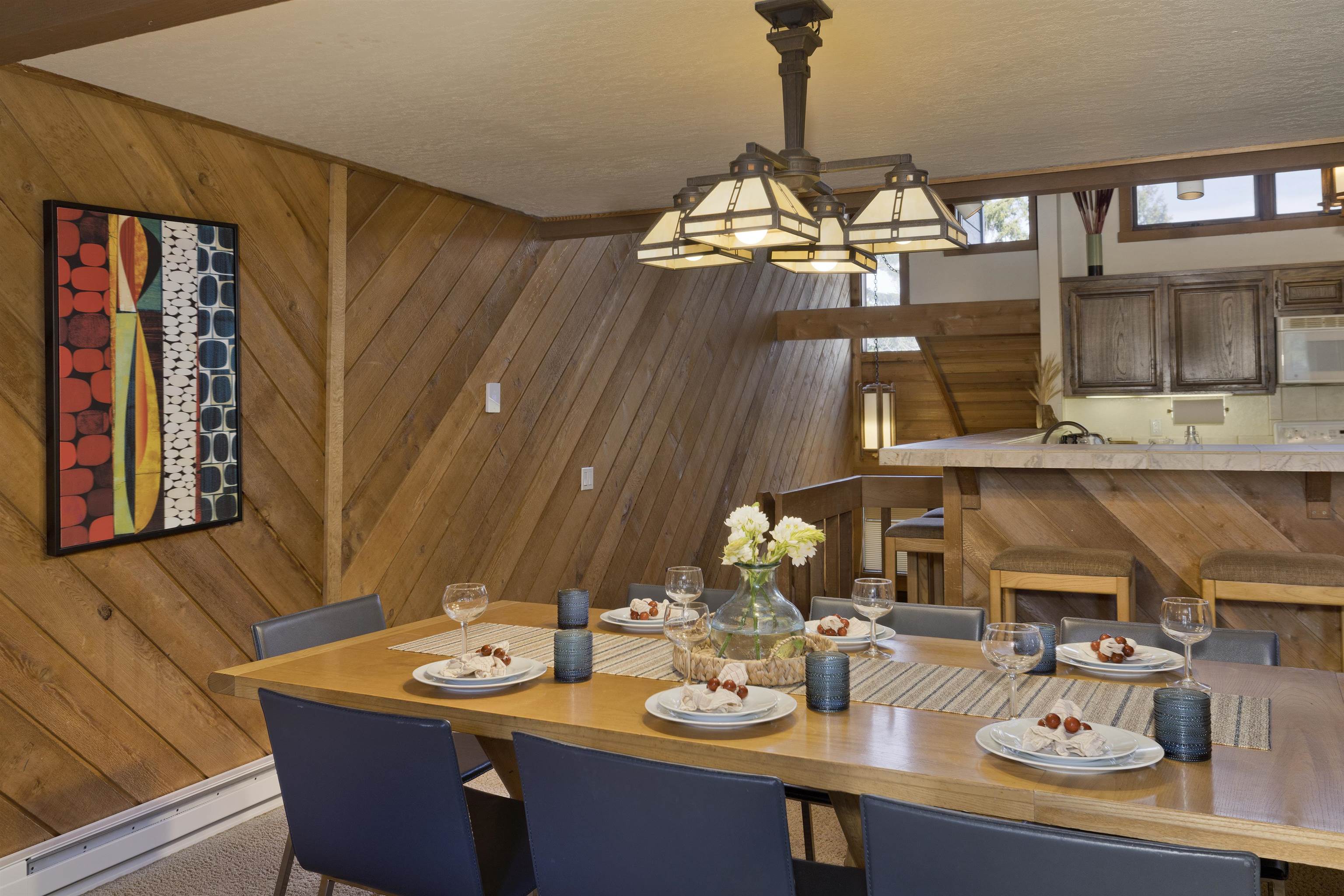 417 Snowcreek Road, Unit 417 Mammoth Lakes, CA 93546 - Photo 7 of 31 Dining area featuring wood-finish wall paneling, a wooden dining table, and an overhead multi-light fixture