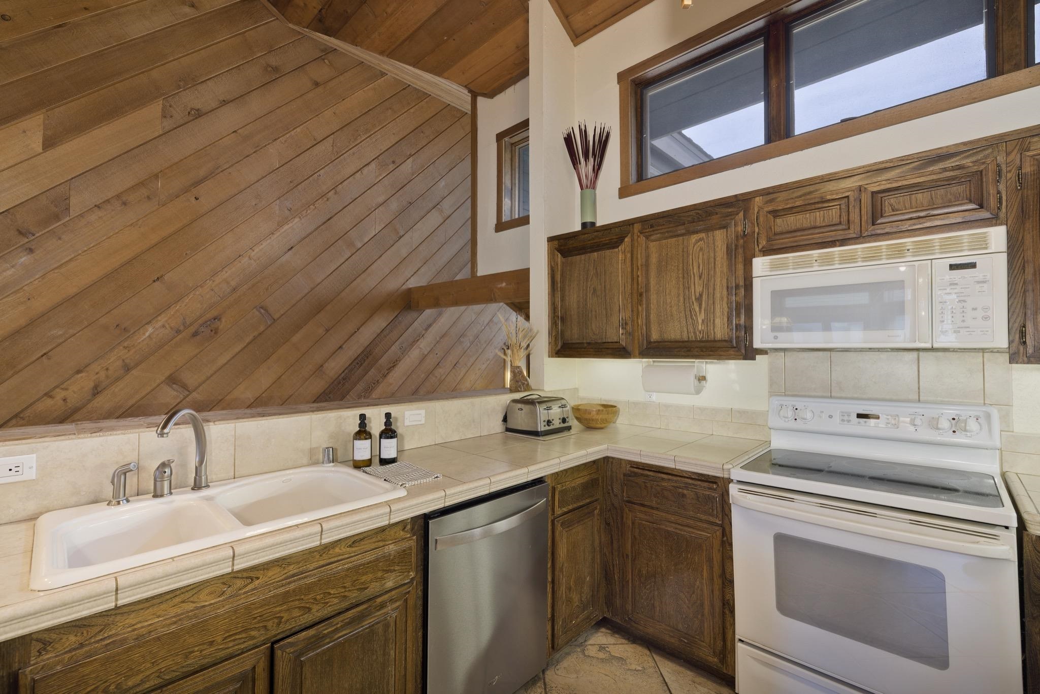 417 Snowcreek Road, Unit 417 Mammoth Lakes, CA 93546 - Photo 10 of 31 Kitchen featuring wood cabinetry, an integrated microwave, a built-in electric range, a double basin sink, and tile countertops