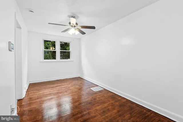 an empty room with wooden floor fan and windows