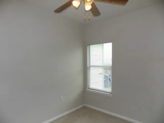an empty room with a window and a fan
