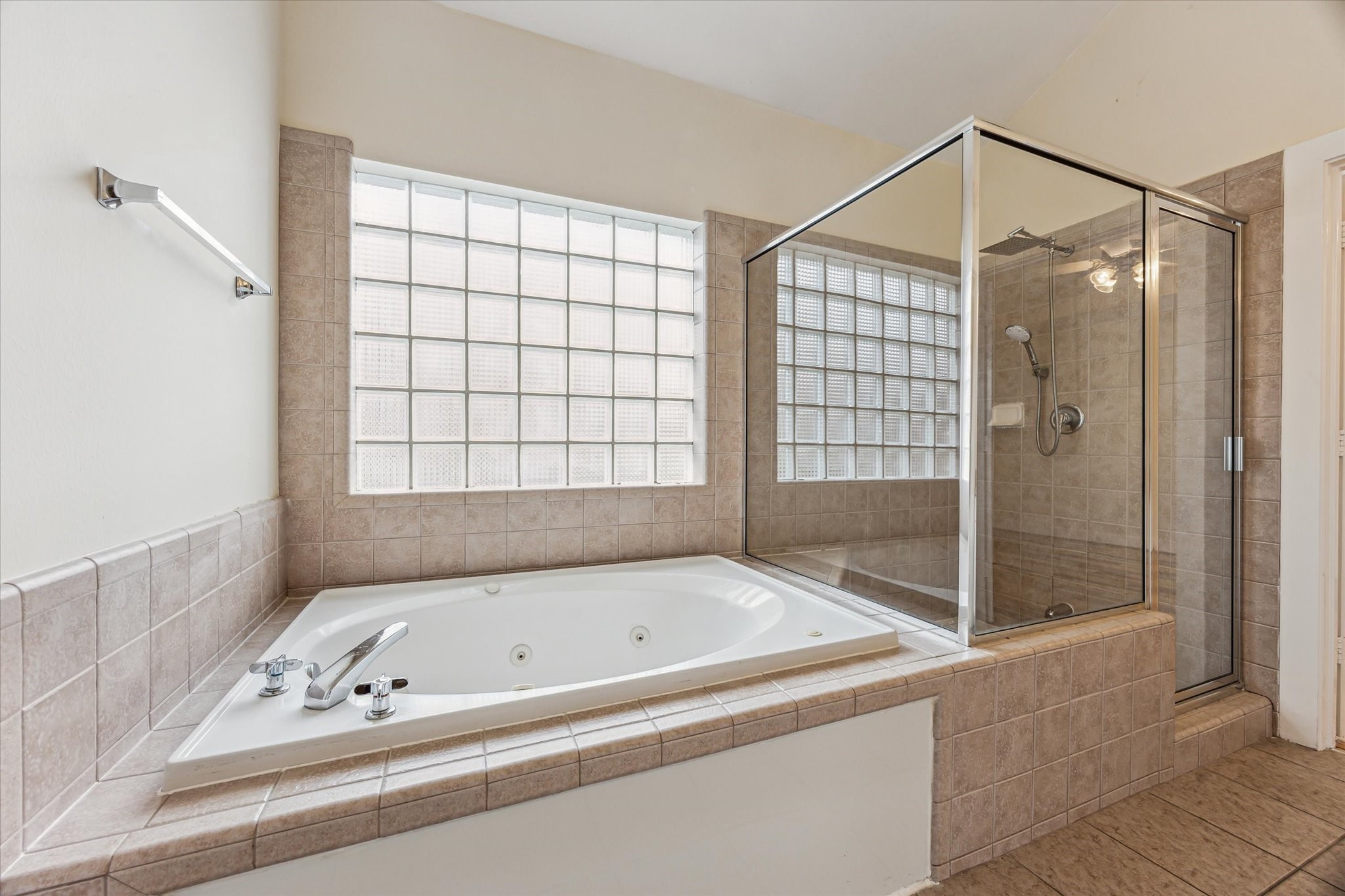 9829 Riddlelink Lane Houston, TX 77025 - Photo 11 of 22 Enjoy a relaxing spa-style bath or a quick rinse in the separate glass-enclosed shower with neutral tile finishes and glass block windows for soft natural light.