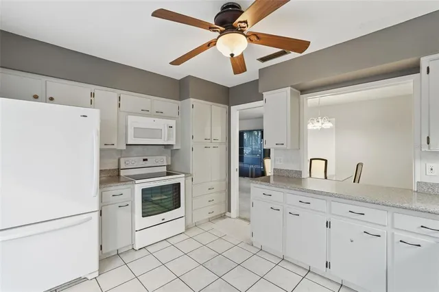 a kitchen with granite countertop white cabinets white stainless steel appliances with a sink and dishwasher