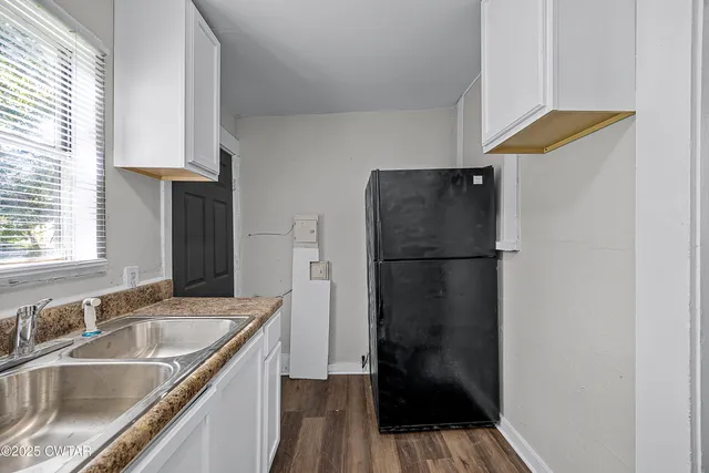 a kitchen that has a sink and a stove with wooden floor