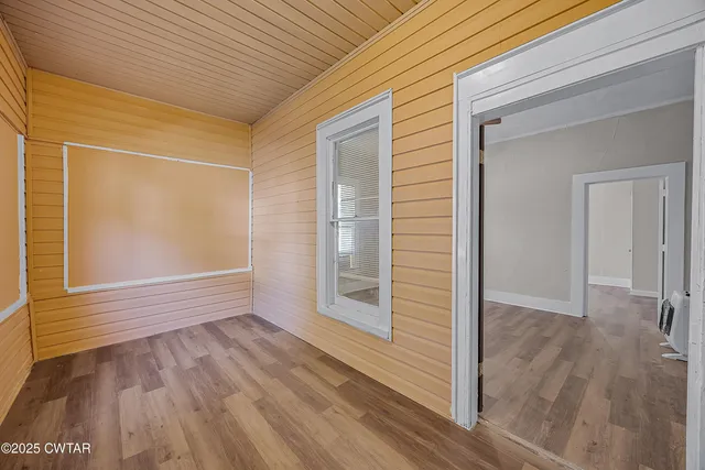 an empty room with wooden floor ceiling fan and windows