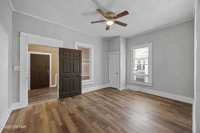 a view of empty room with wooden floor and fan