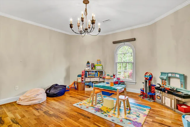 a bedroom with a bed chandelier and a window