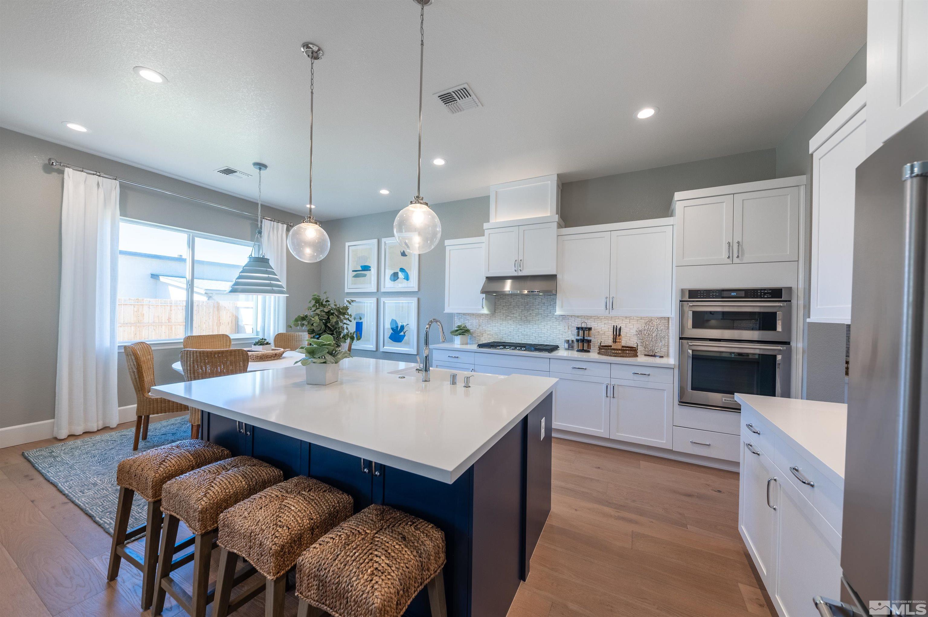 12519 Blue Stream Street, Unit HOMESITE 138 Reno, NV 89521 - Photo 4 of 9 a kitchen with stainless steel appliances granite countertop a table chairs sink refrigerator and cabinets