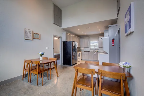 a kitchen with stainless steel appliances kitchen island granite countertop a refrigerator and a dining table