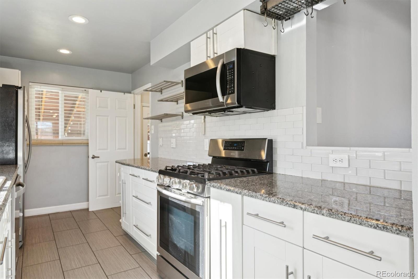 81 South Ingalls Street Lakewood, CO 80226 - Photo 12 of 29 a kitchen with stainless steel appliances granite countertop a stove a microwave and a sink