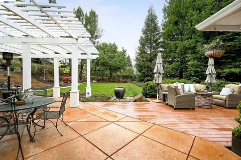 a view of a patio with table and chairs potted plants with floor to ceiling window and wooden fence