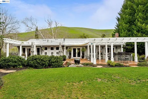 a view of a patio with table and chairs potted plants and large tree