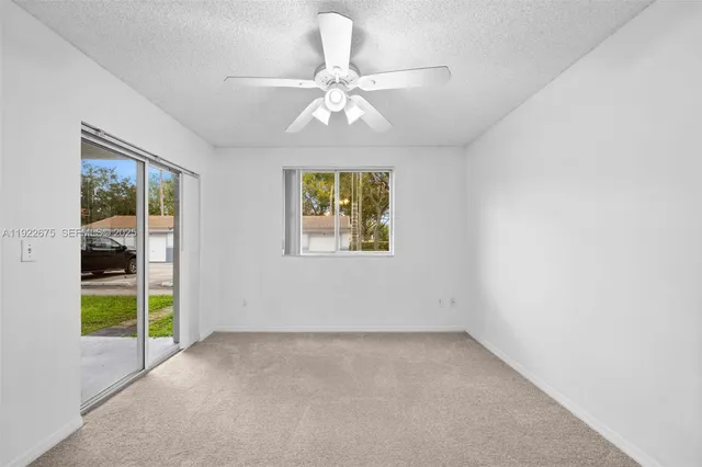an empty room with a ceiling fan and a window
