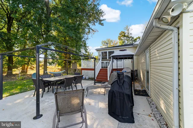 a view of a patio with table and chairs and floor to ceiling window plants and trees
