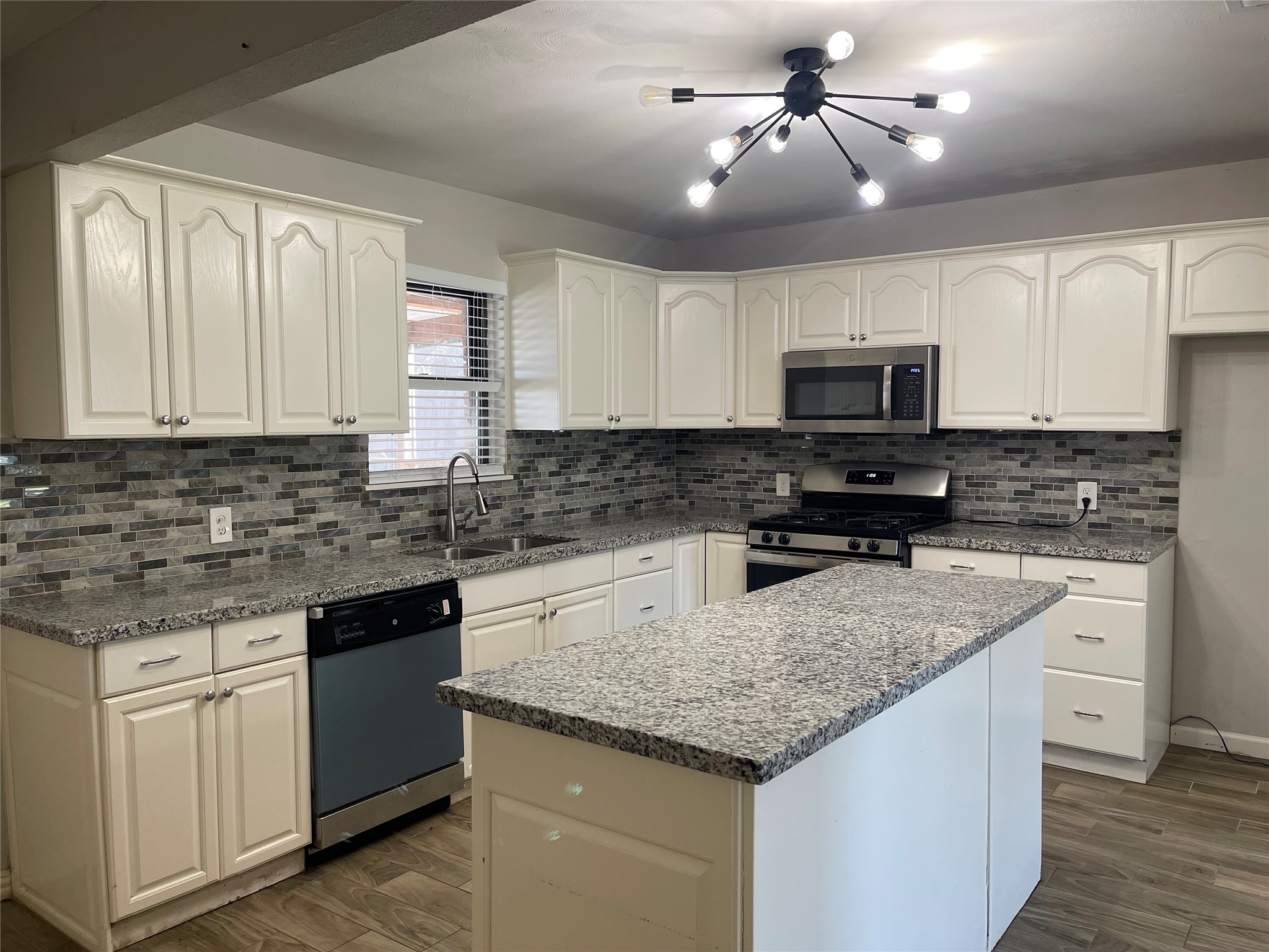 300 Hargett Street Clute, TX 77531 - Photo 8 of 36 a kitchen with kitchen island granite countertop a sink stainless steel appliances and white cabinets