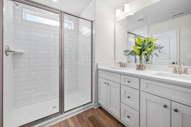 a bathroom with a double vanity sink mirror and shower