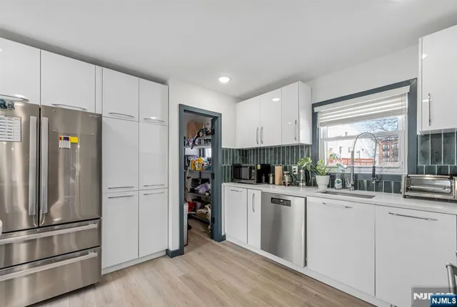 a kitchen with stainless steel appliances a refrigerator and wooden floor