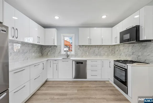a kitchen with white cabinets appliances and sink