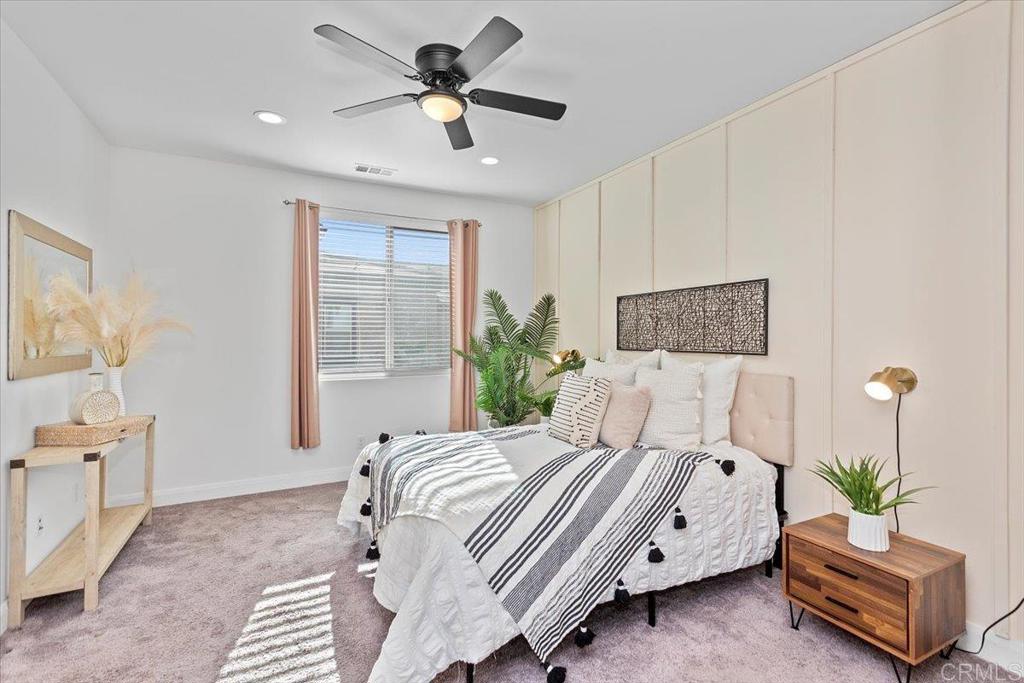 2465 Solara Lane Vista, CA 92081 - Photo 23 of 48 a bedroom with a bed a couch and a potted plant