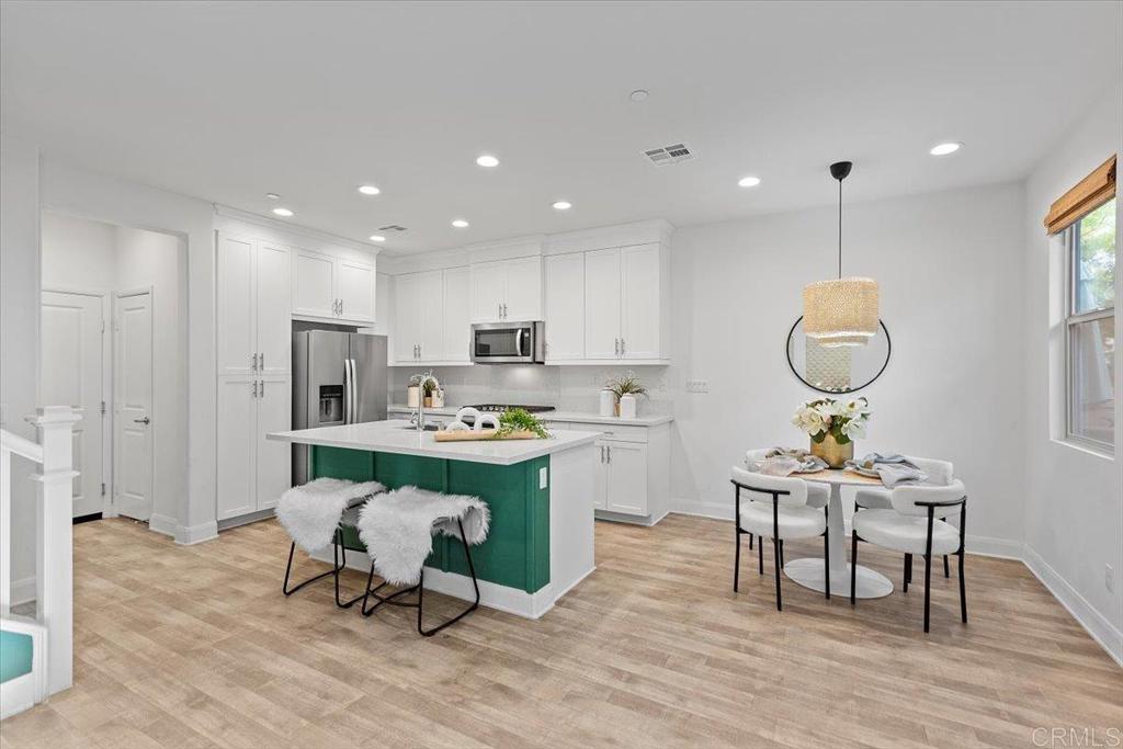 2465 Solara Lane Vista, CA 92081 - Photo 7 of 48 a room with stainless steel appliances kitchen island granite countertop a dining table chairs and a refrigerator