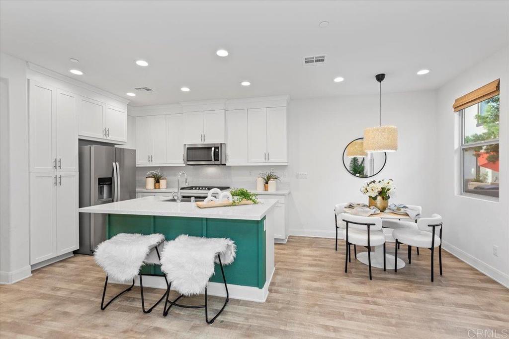 2465 Solara Lane Vista, CA 92081 - Photo 8 of 48 a room with stainless steel appliances kitchen island granite countertop a dining table chairs and a refrigerator