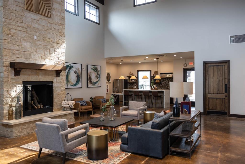 153 Cabrera Street Oak Point, TX 75068 - Photo 21 of 22 Spacious open-concept Community living area featuring a floor-to-ceiling stone fireplace with a wood mantle, high ceilings, large windows, and polished concrete flooring
