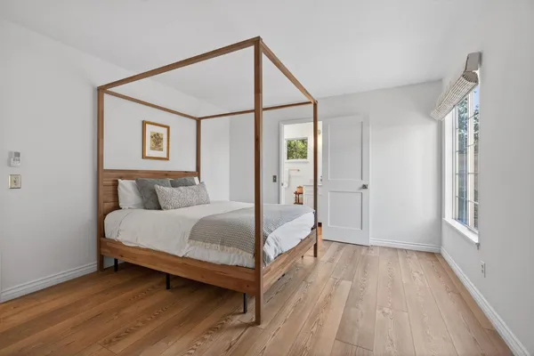 a spacious bedroom with a bed and a wooden floor