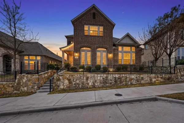 a front view of a house with large trees and outdoor space