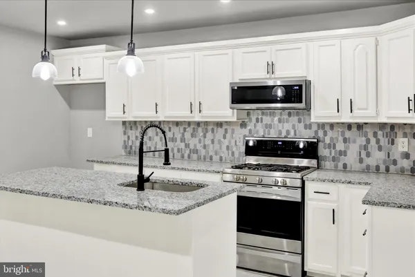 a kitchen with stainless steel appliances granite countertop a sink a stove and a microwave
